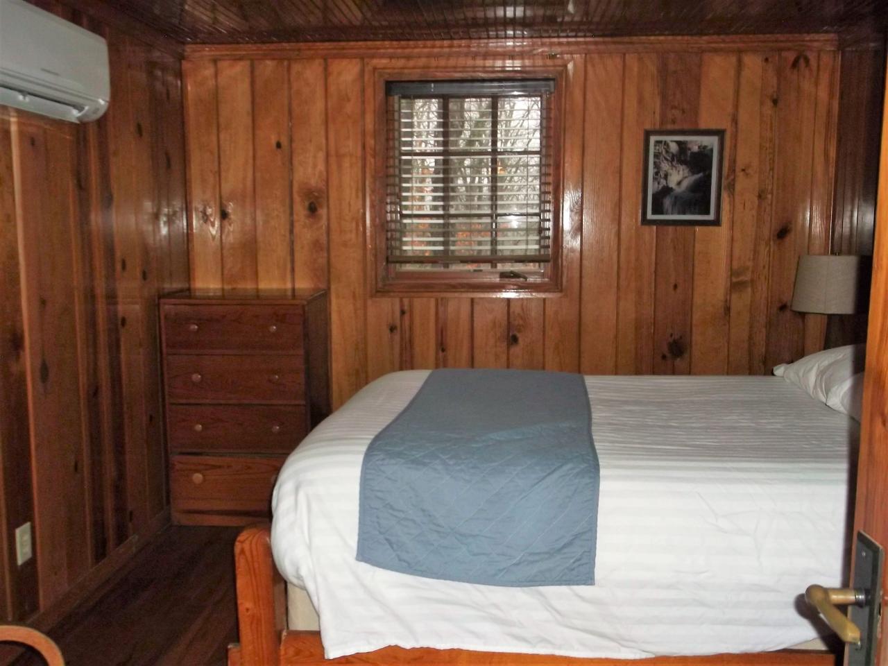 A view of one of the bedrooms at cabin 11 including a bed, dresser and exterior window